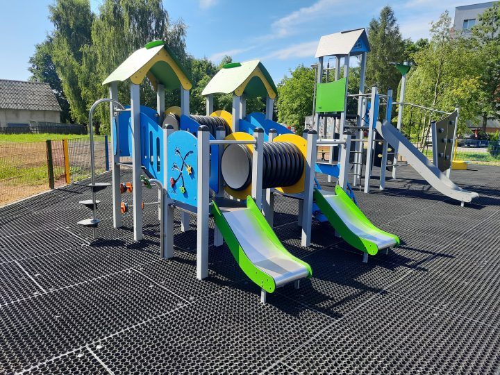 Duża konstrukcja zabawowa w kolorach niebieski, zielony i żółty ze zjeżdżalniami i utrudnieniami do przejścia.