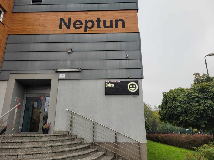 A building with "Neptun" prominently displayed, featuring a staircase and a sign with a smiley face.