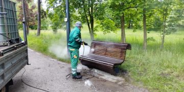 Pracownik myje parkową ławkę
