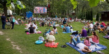 ludzie na kocach w plenerze, oglądają film na ekranie